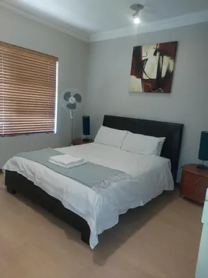 a bedroom with a large bed with a fan at Premium Getaway @ la Bella Costa in Pretoria