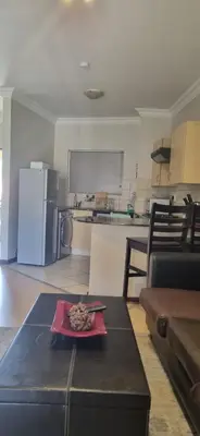 a living room with a table and a kitchen at Premium Getaway @ la Bella Costa in Pretoria