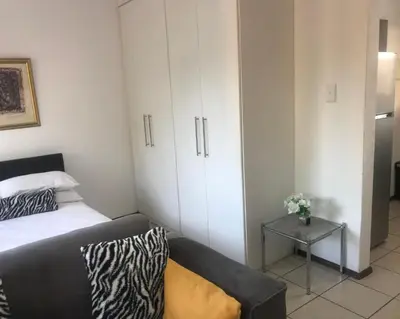 a room with a bed and a couch and cabinets at Studio Eazi in Midrand