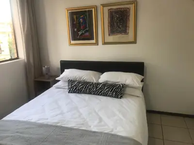a white bed with two pillows on top of it at Studio Eazi in Midrand
