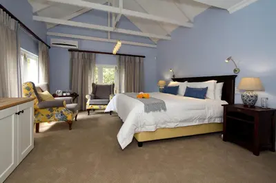 a large bedroom with a large bed and chairs at The Rose Cottage B&B in Dullstroom