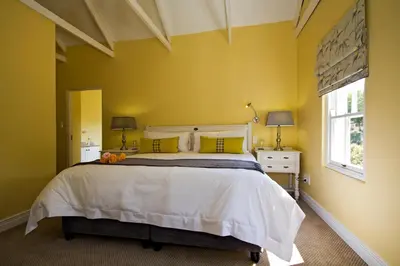 a bedroom with a large bed and a yellow wall at The Rose Cottage B&B in Dullstroom