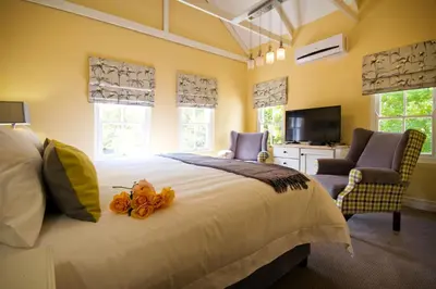 a bedroom with a bed and two chairs and a television at The Rose Cottage B&B in Dullstroom