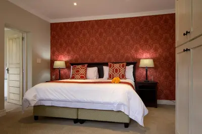 a bedroom with a large bed with a red wall at The Rose Cottage B&B in Dullstroom