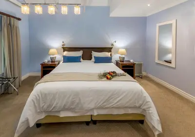 a bedroom with a large bed with blue walls at The Rose Cottage B&B in Dullstroom