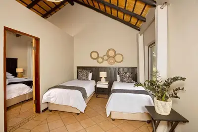 a bedroom with two beds and a mirror at Unyati Safari Lodge in Hectorspruit