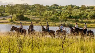 a group of people riding horses in the water at Unyati Safari Lodge in Hectorspruit