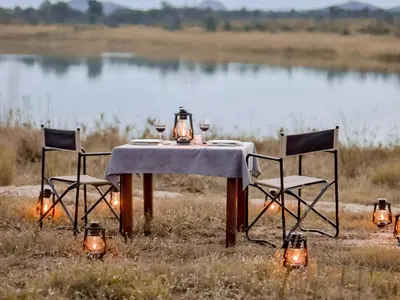 a table and chairs with wine glasses and lights at Unyati Safari Lodge in Hectorspruit