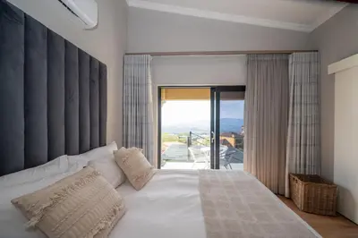 a bedroom with a white bed with a large window at Utopia on the Rock1 in Nelspruit