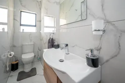a white bathroom with a sink and a toilet at Utopia on the Rock1 in Nelspruit