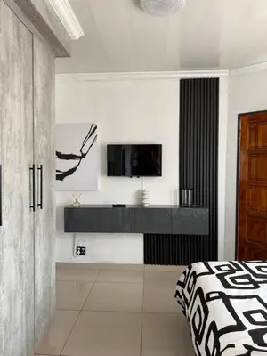 a bedroom with a bed and a tv on a wall at Studios at Monarch Inn in Polokwane
