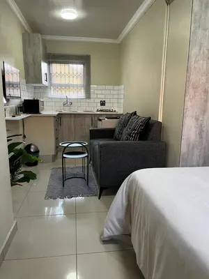 a living room with a couch and a kitchen at Studios at Monarch Inn in Polokwane