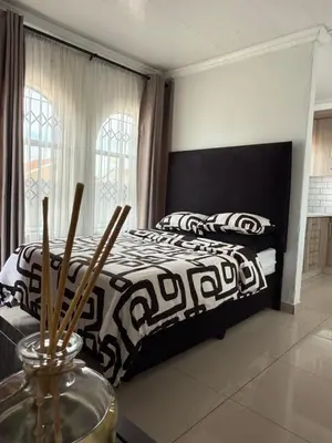 a bedroom with a bed with a black and white comforter at Studios at Monarch Inn in Polokwane