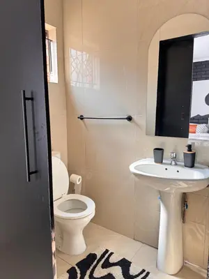 a bathroom with a white toilet and a sink at Studios at Monarch Inn in Polokwane