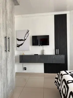 a living room with a tv on a wall at Studios at Monarch Inn in Polokwane