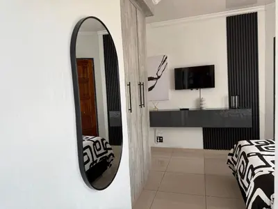 a mirror on a wall in a room at Studios at Monarch Inn in Polokwane