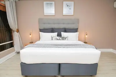 a large white bed with two cats sitting on it at Menlyn Maine - The Smart Home in Pretoria