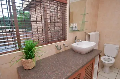 a bathroom with a sink and a toilet and a window at Menlyn Maine - The Smart Home in Pretoria