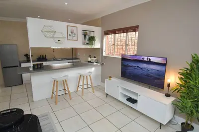 a kitchen with a flat screen tv and a counter at Menlyn Maine - The Smart Home in Pretoria