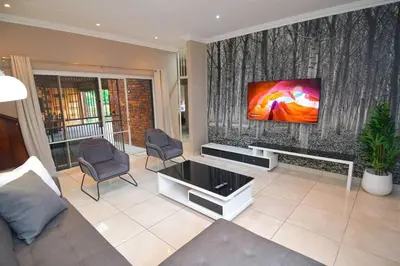 a living room with a flat screen tv on a wall at Menlyn Maine - The Smart Home in Pretoria