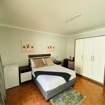 a bedroom with a bed with white cabinets and a rug at 473 On Cliff in Pretoria