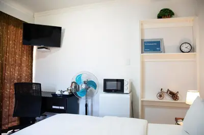 a room with a bed and a desk with a fan at The Affectionate One in Louis Trichardt