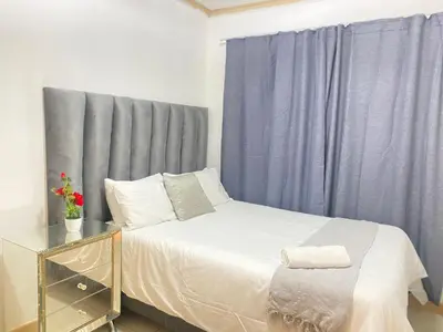 a bedroom with a bed with a blue curtain at Siena Sun Luxury Apartment 6 in Midrand