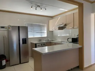 a kitchen with a stainless steel refrigerator and cabinets at Siena Sun Luxury Apartment 6 in Midrand
