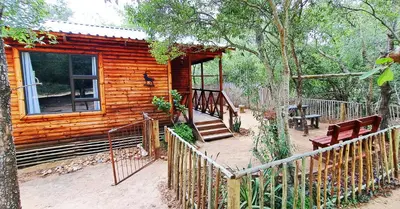 a log cabin with a porch and a wooden fence at Kruger Maroela Lodge in Marloth Park