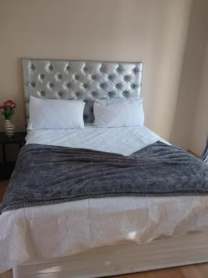 a large bed with a gray blanket and pillows at Home Life Guesthouse in Midrand