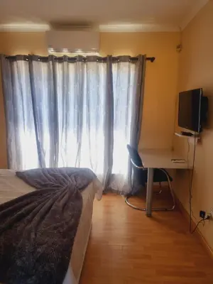 a bedroom with a bed and a desk and a window at Home Life Guesthouse in Midrand