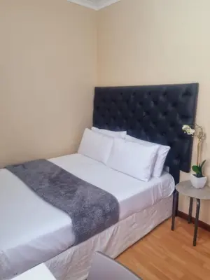 a bedroom with a large bed with a black headboard at Home Life Guesthouse in Midrand