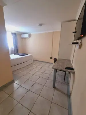 a small room with a bed and a table in it at Home Life Guesthouse in Midrand