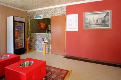 a red wall in a room with red stools at Home Life Guesthouse in Midrand