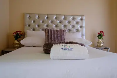 a white bed with two pillows on top of it at Home Life Guesthouse in Midrand