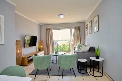 a living room with a couch and a table and chairs at Unit 309 at Menlyn Place in Pretoria