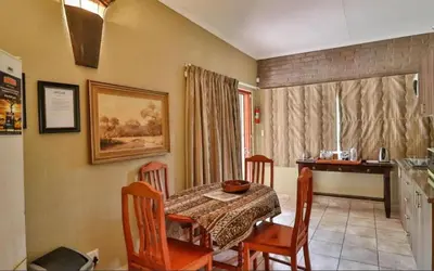 a dining room with a table and chairs and a kitchen at Mispel House self catering holiday accommodation in Komatipoort