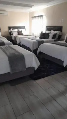a hotel room with four beds in a room at Lasev Resort in Pretoria