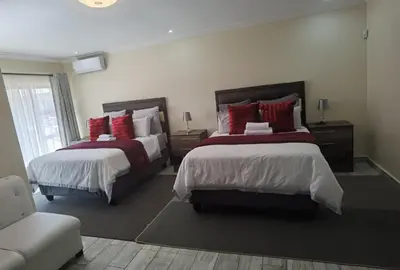 a bedroom with two beds with red pillows at Lasev Resort in Pretoria