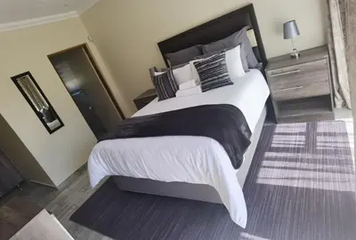 a bedroom with a large bed with white sheets and pillows at Lasev Resort in Pretoria