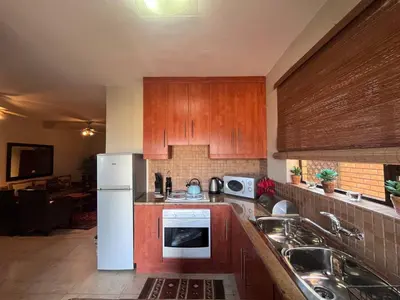 a kitchen with wooden cabinets and a white refrigerator at Lake house retreat in Haenertsburg