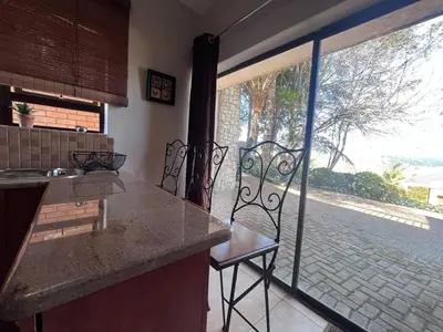 a kitchen with a counter with two chairs and a large window at Lake house retreat in Haenertsburg