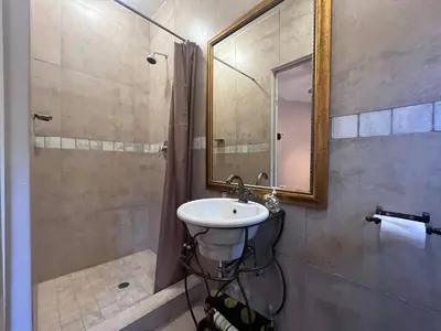 a bathroom with a sink and a shower with a mirror at Lake house retreat in Haenertsburg