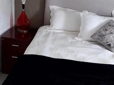 a bed with white sheets and pillows and a red lamp at 46 Charles Bed and Breakfast in Tierpoort