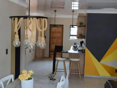 a kitchen with a table and chairs and a counter at Tshepang Apartments Secunda in Secunda