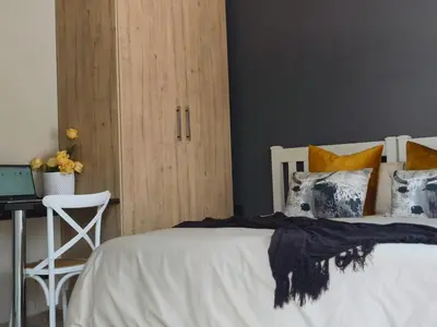a bedroom with a white bed with pillows and a desk at Tshepang Apartments Secunda in Secunda