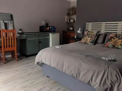 a bedroom with a large bed with a desk and a chair at White River Stay in White River