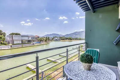 a table on a balcony with a view of a river at 2 Lanner holiday home in Hartbeespoort