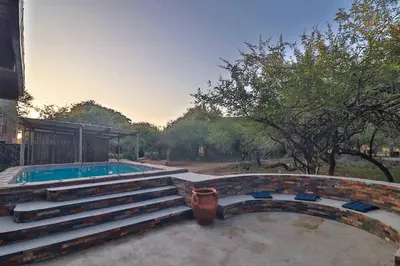 a swimming pool with a staircase next to a house at P.A.P.E's RETREAT in Marloth Park