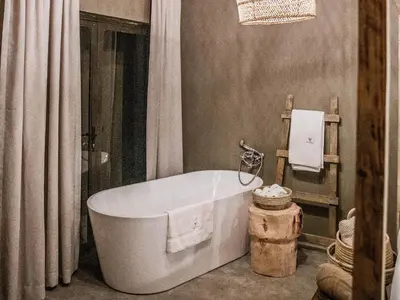 a white bath tub in a bathroom with curtains at Minara Private Boutique Game Lodge in Dinokeng Game Reserve